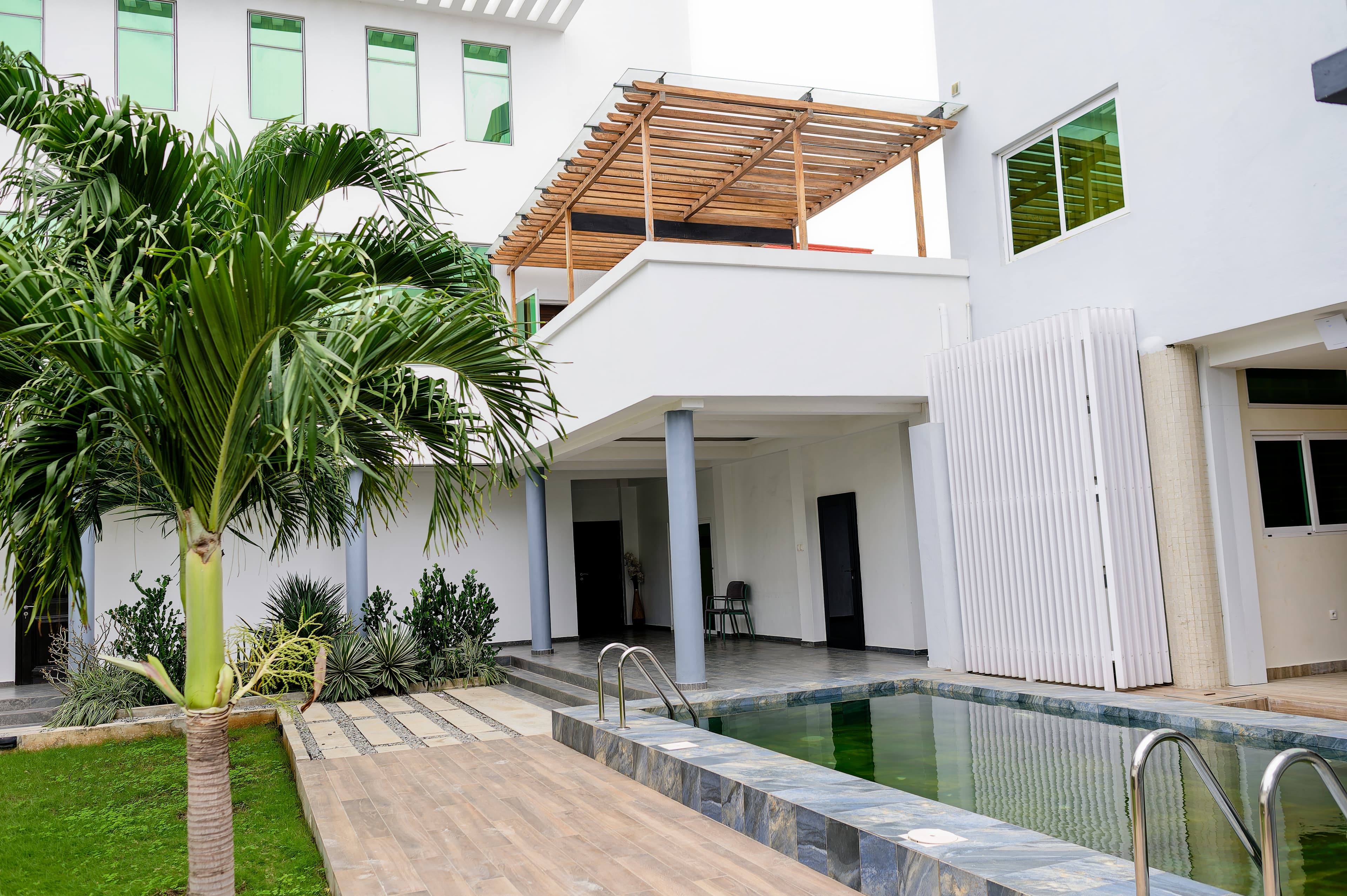 La Piscine extérieure bordée de palmiers, près d'un jardin luxuriant